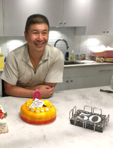 man satnding at counter with birthday cake