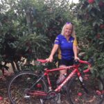 woman standing beside bike in an apple orchard